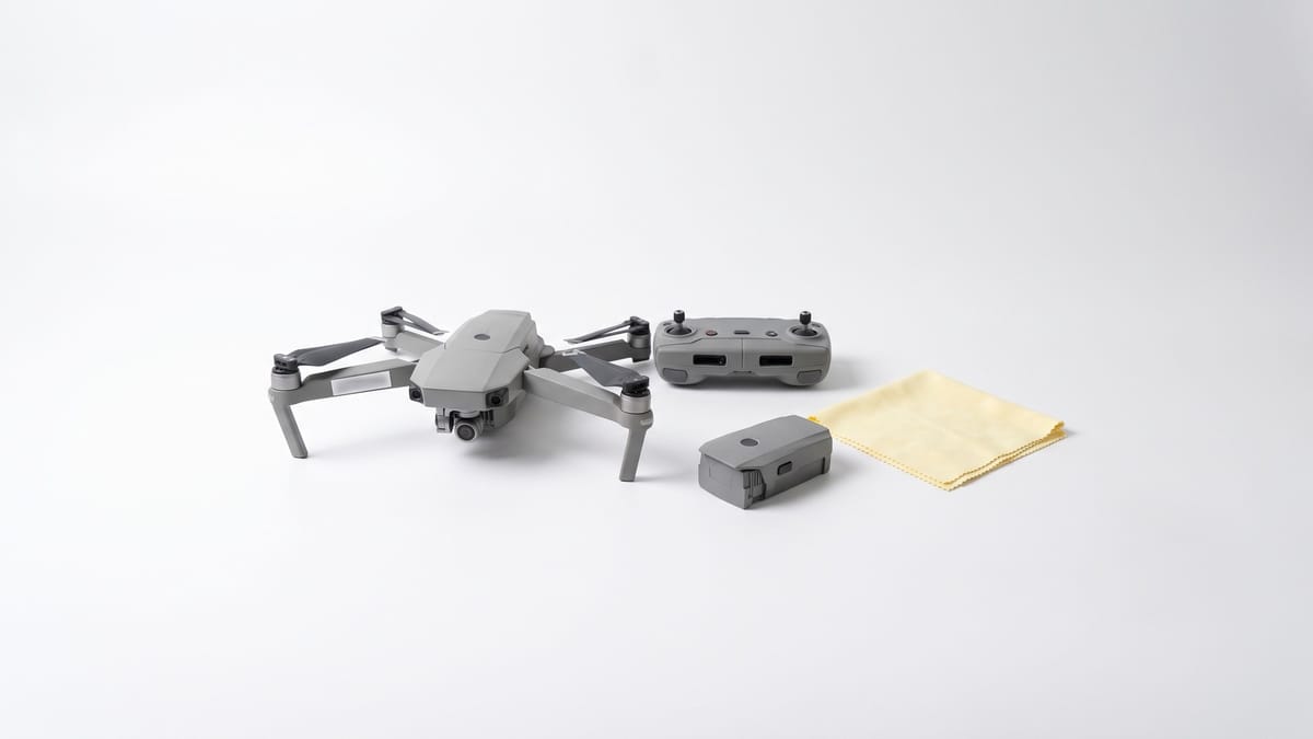 Piccolo drone pieghevole chiuso accanto al radiocomando su fondo bianco