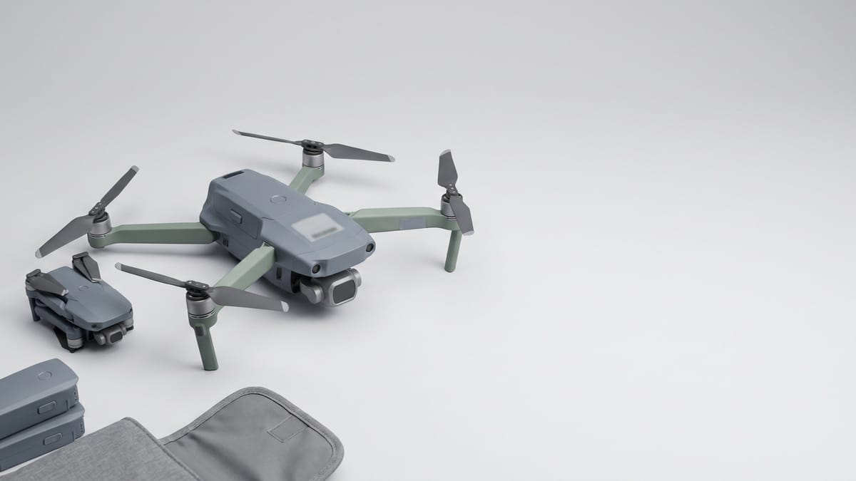 Drone di media taglia affiancato a uno più piccolo su fondo grigio chiaro